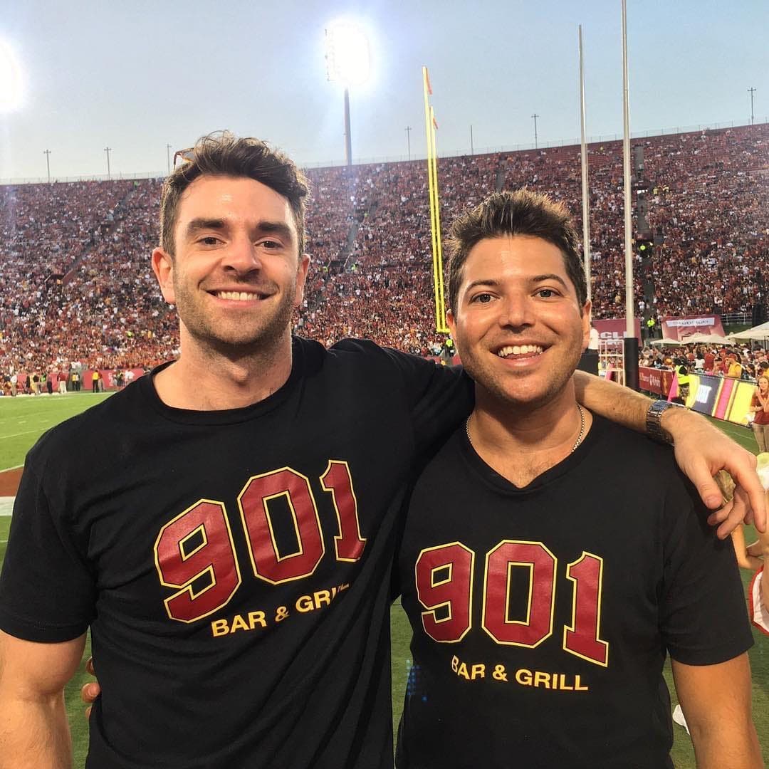 Two friends wearing 901 Bar & Grill shirts at the Coliseum under the stadium lights