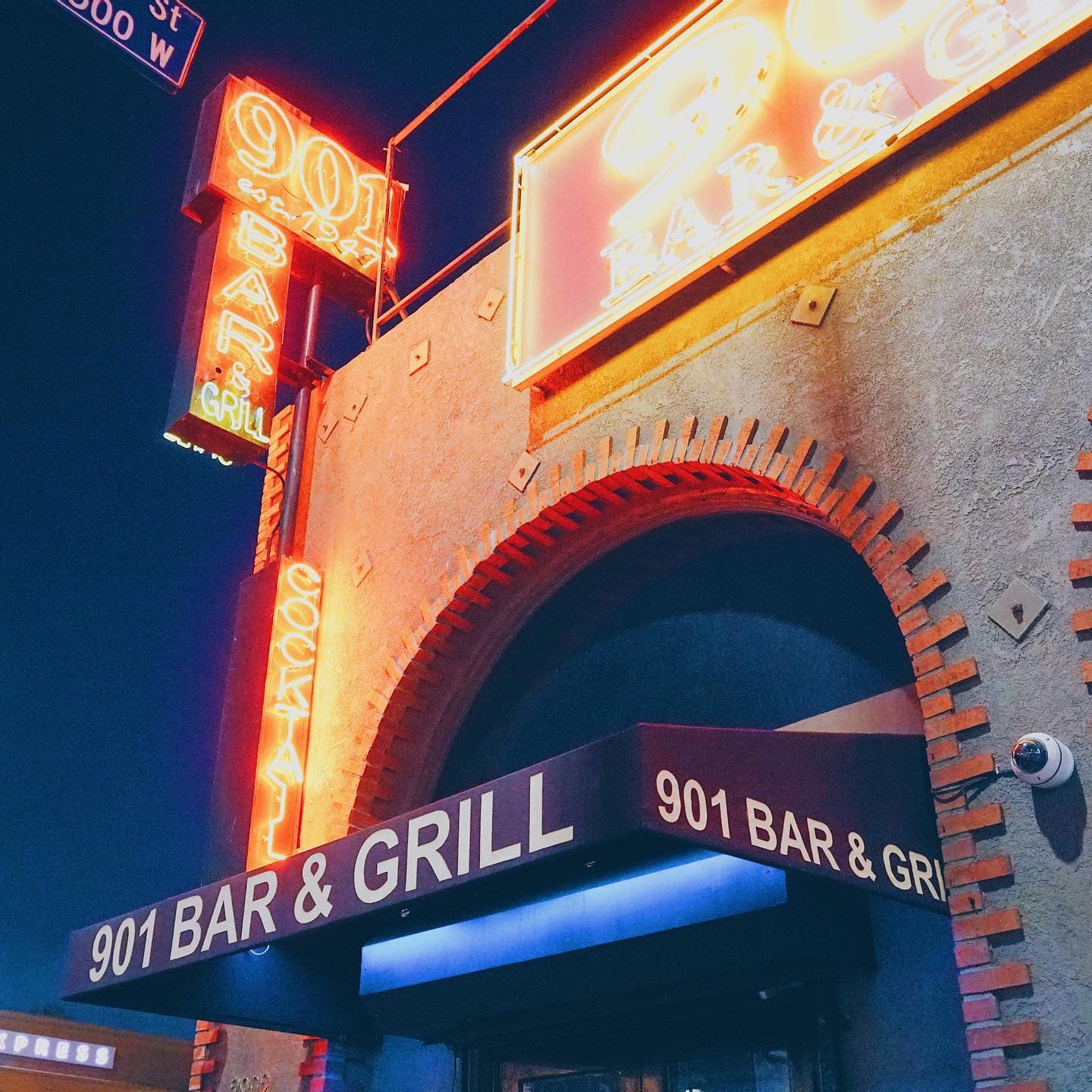 The 901 Bar & Grill neon blade sign glowing above the brick arch entrance on South Figueroa at night