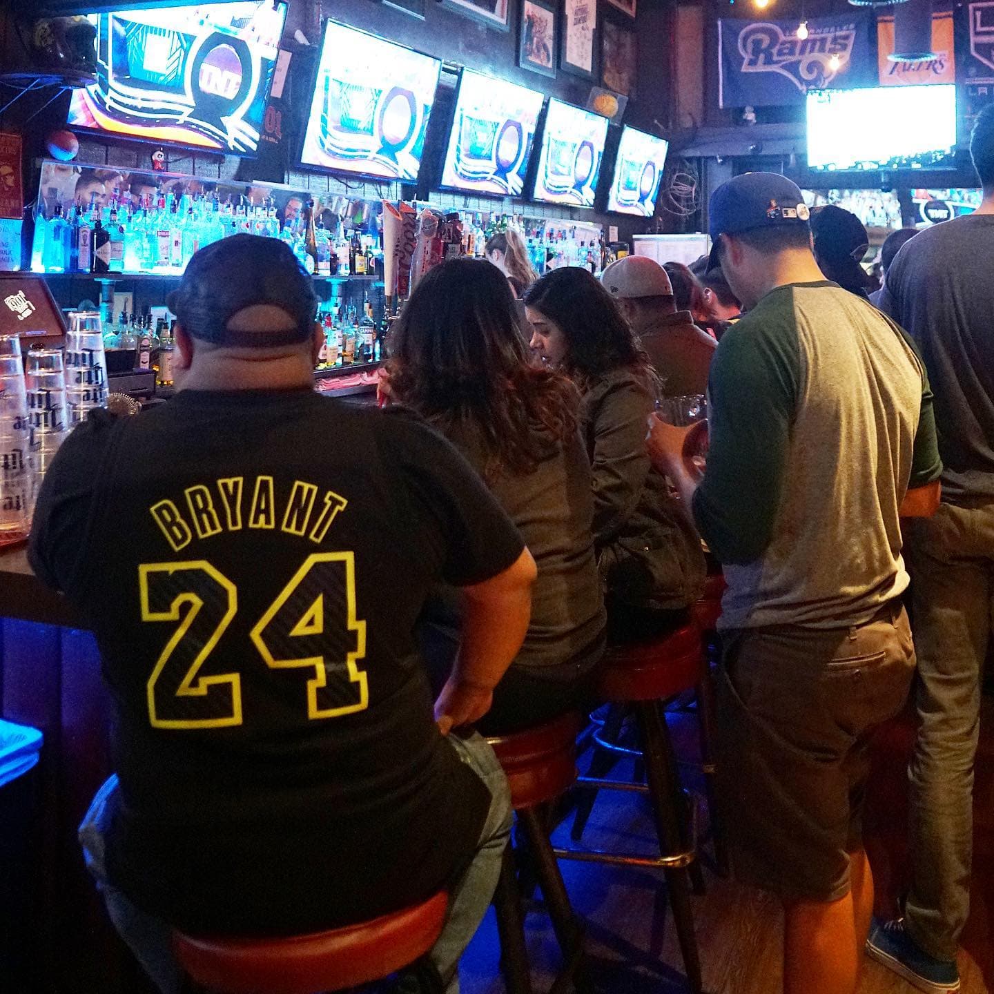 The back bar at 901 under a wall of screens, with fans on stools watching