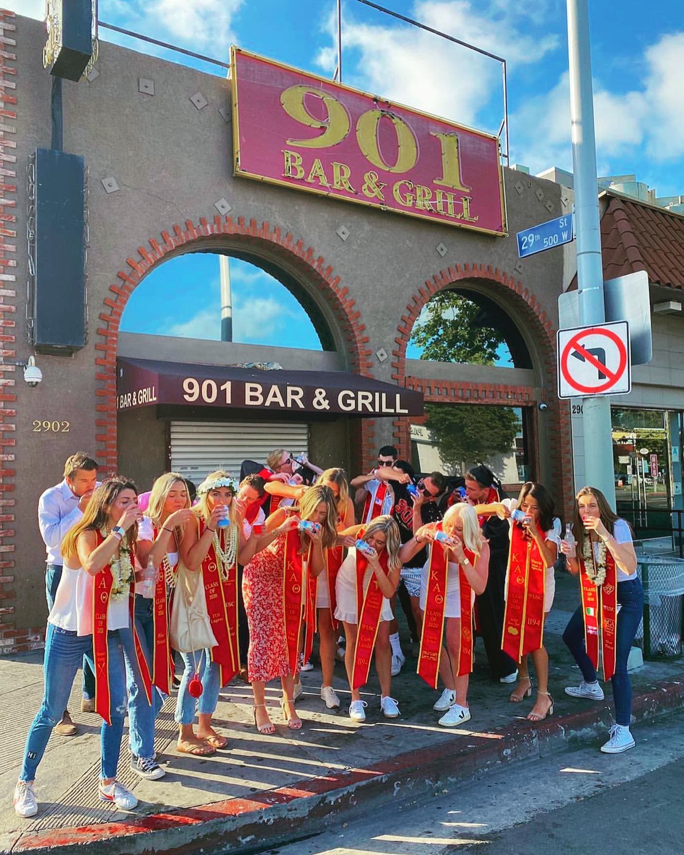 Graduating students in cardinal sashes gathered outside the 901 entrance arch
