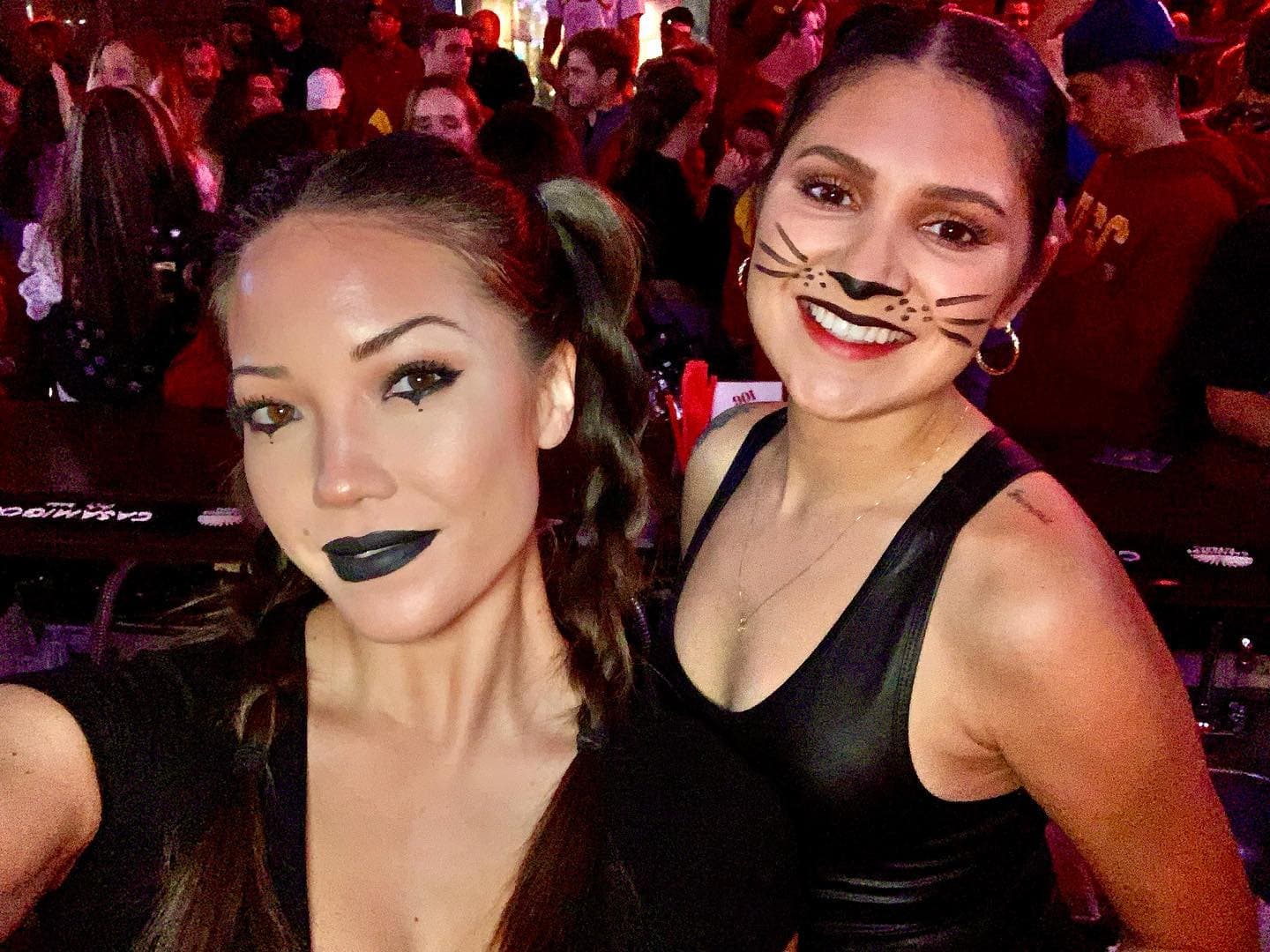 Two people in Halloween face paint and makeup in the middle of a packed room