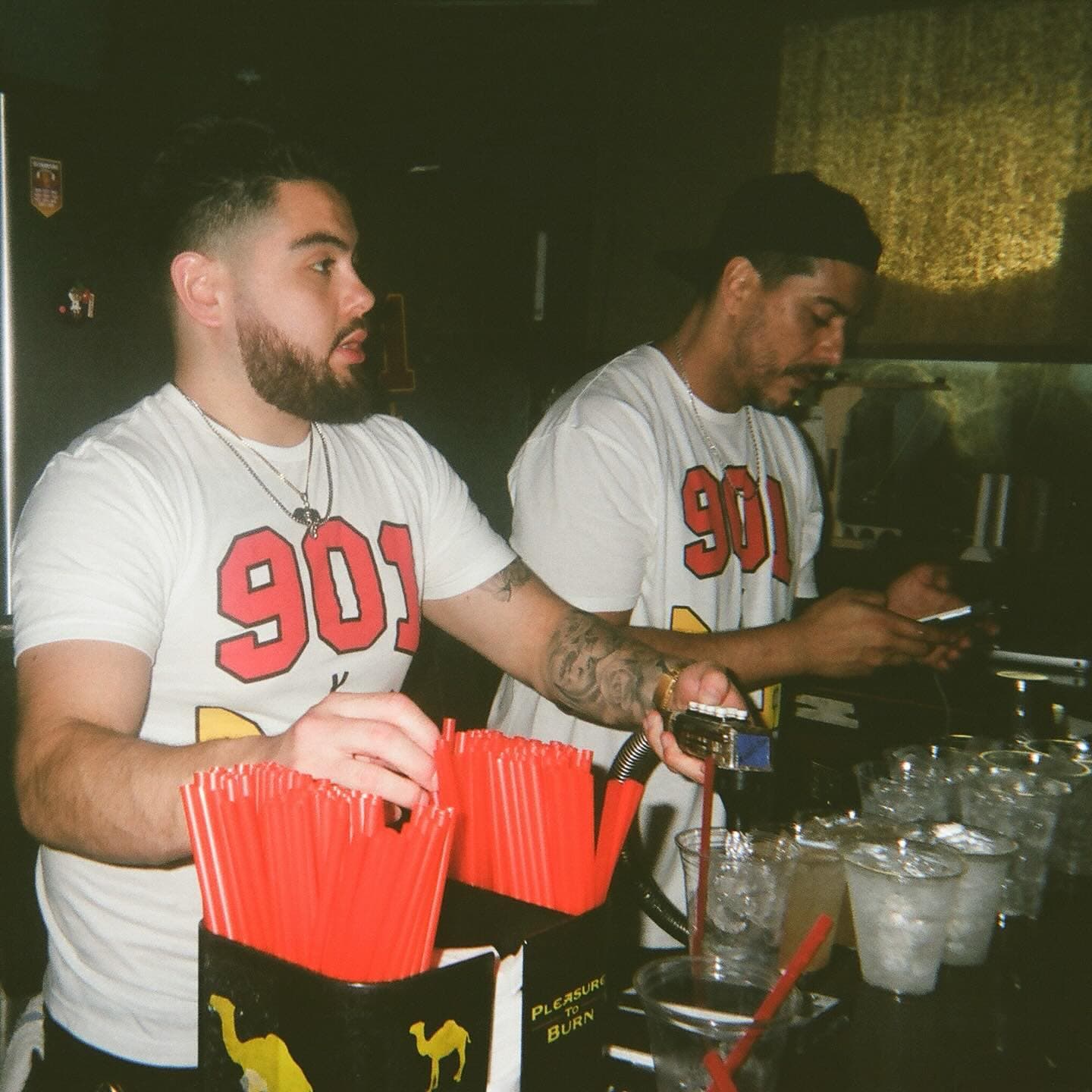Two bartenders in 901 Bar & Grill shirts making drinks behind the bar