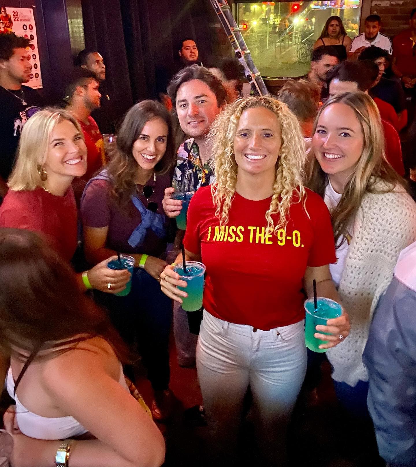 A group of friends at the bar, one of them wearing a cardinal shirt reading I miss the 9-0